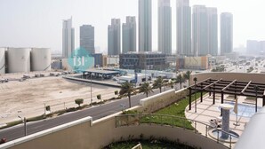 Zona urbana com edifícios modernos altos, uma estrada e área ajardinada com piscina.