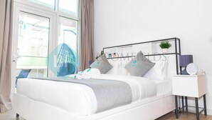 Une chambre à coucher moderne avec un lit, une table de chevet et une vue sur l’extérieur.