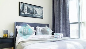 Cama bem arrumada com lençóis brancos, cabeceira preta e quadro emoldurado acima.