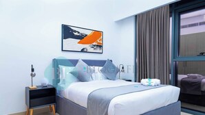 Quarto moderno com cama, mesa de cabeceira, abajur e janela com cortinas.
