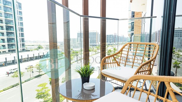 A balcony with wicker furniture, a small table with a potted plant, and a city view. - Bloomfields STU City View Azizi Riviera Meydan (Dubai)