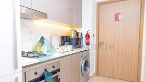 A compact kitchen with a built-in oven, microwave, and coffee maker. - Bloomfields STU City View Azizi Riviera Meydan (Dubai)
