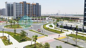 A modern urban intersection with a multi-level highway overpass, surrounded by greenery and contemporary buildings. - Bloomfields STU City View Azizi Riviera Meydan (Dubai)