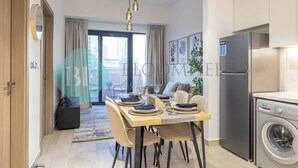 Een moderne keuken met een inbouw wasmachine, een eethoek met een tafel gedekt voor twee personen en een stadszicht door het raam.
