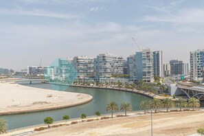 A coastal cityscape with modern high-rise buildings, a marina, and a sandy beach.