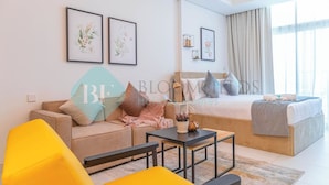 A modern hotel room with a sofa, a bed, a small table, and framed artwork on the walls. - Bloomfields Spacious STU in Thalassa Beach Front (Abu Dabi)