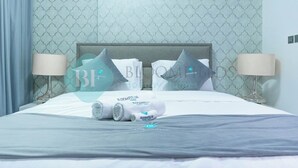 A hotel room with a neatly made bed, two bedside lamps, and patterned wallpaper.