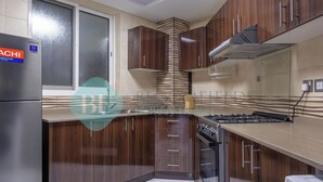 A modern kitchen with dark wood cabinets, a stainless steel refrigerator, and a built-in gas stove.