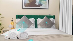 A neatly made bed with white linens and two pillows, a bedside table with a lamp, and a framed artwork on the wall. - Bloomfields Fantastic STU Azizi Riviera Meydan (Dubai)