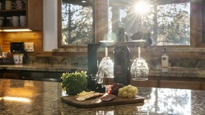 Un comptoir de cuisine avec un carafe à vin en verre, une bouteille et un plateau de fruits.
