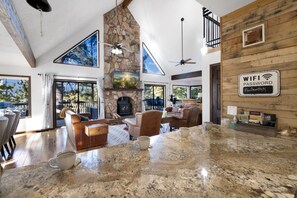 A spacious living area with a stone fireplace, a large dining table, and a sign indicating WIFI availability. - Hot tub, In-Home Bar, Arcade Game, Wood Fireplaces, Xbox, Grill, Sleeps up to 16 (Flagstaff)