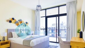 Ett modernt hotellrum med en stor säng, ett skrivbord, en stol och en balkong med utsikt över staden.