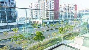 Un bâtiment moderne doté de grandes fenêtres donnant sur une rue bordée de palmiers et où sont garées des voitures.