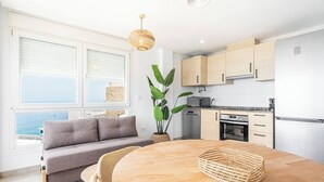 Eine moderne Küche mit Holzausstattung, einem Esstisch mit Stühlen und Meerblick durch große Fenster.