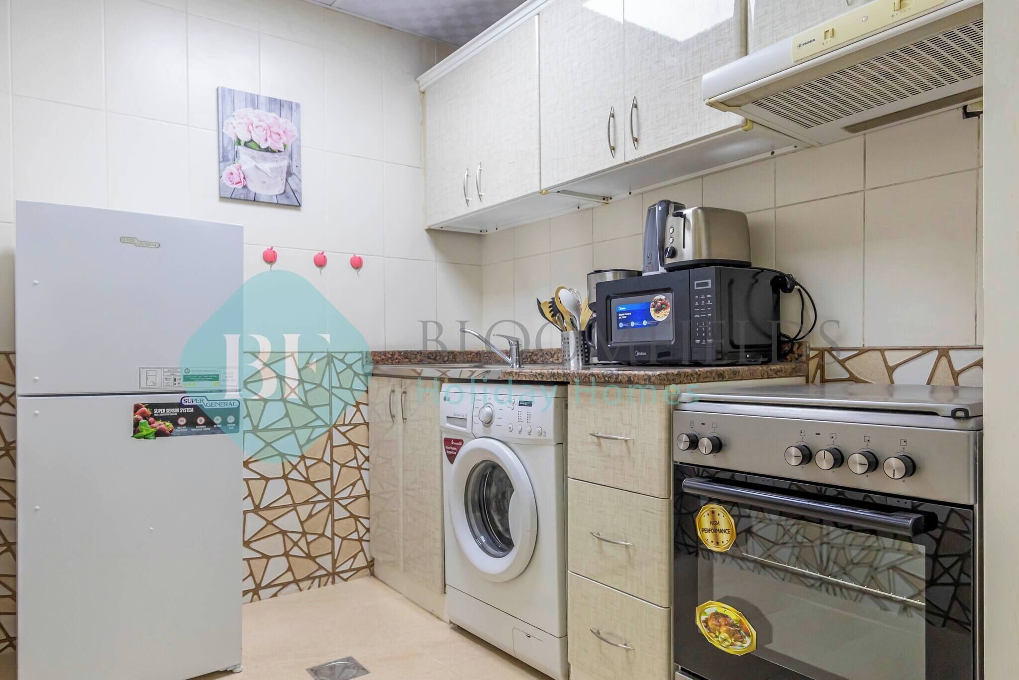A compact kitchen with a refrigerator, washing machine, microwave, and oven.