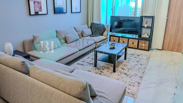 Una sala de estar con un sofá, una mesa de centro, un televisor y cuadros en la pared.