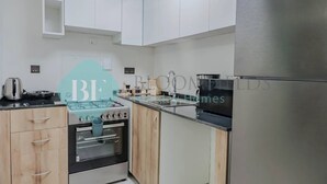 Una cocina moderna con armarios blancos, un refrigerador de acero inoxidable, una estufa a gas y un horno empotrado.