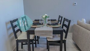 Una mesa de comedor dispuesta con individuales, copas de vino y un florero.