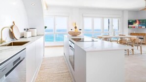 A modern kitchen with a central island, large windows, and a view of the ocean.
