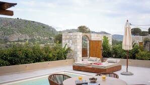A rooftop terrace with a pool, seating area, and a view of the surrounding landscape. - Pure Nature (Hersonissos)