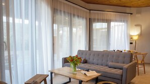 A modern living room with a grey sofa, a wooden coffee table, and a small side table. - Pure Nature (Hersonissos)