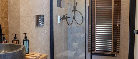 A modern bathroom with a glass-enclosed shower, a wooden vanity, and a toilet with a towel.