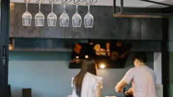 A restaurant interior with hanging light fixtures, a counter, and a view of the kitchen area.