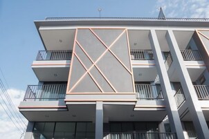 Un edificio de varios pisos con balcones, ventanas amplias y un elemento de diseño geométrico distintivo.