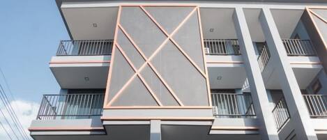 A multi-story building with balconies, a geometric facade, and a clear sky.