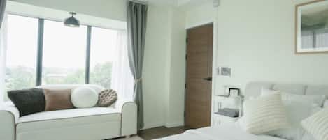 Un dormitorio con cama, sofá, ventana y puerta.
