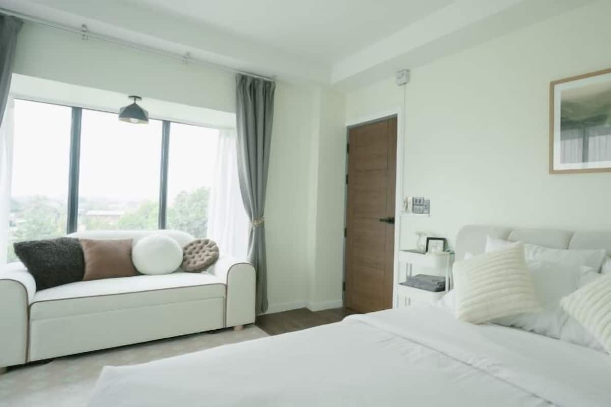 Ein Schlafzimmer mit Bett, Sofa, Nachttisch, Fenster und Tür.