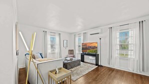 Una sala moderna con un sofá, un reposapiés y un cuadro en la pared.