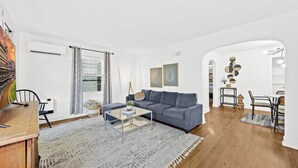 A modern living room with a grey sofa, a glass coffee table, and a wooden dining table with chairs. - Exclusive Louisville king suite near bourbon trail (Louisville)