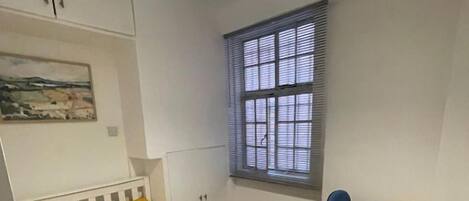 A bedroom with a bed, a window, a chair, and a small desk.