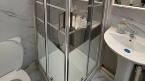 Ein Badezimmer mit Duschkabine, Waschbecken in Weiß und Toilette.