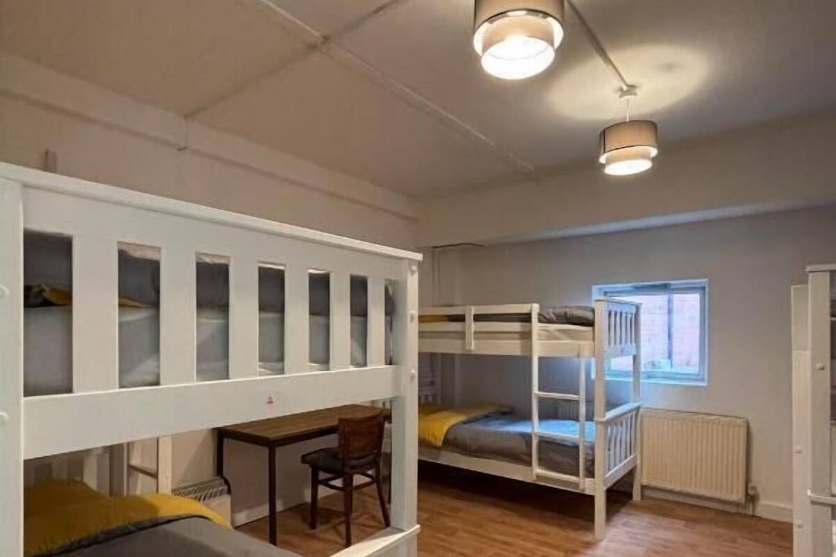 A dormitory room with bunk beds, a desk, and a chair.