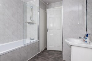Huis | Badkamer | Een bad/douchecombinatie, een diep bad, een haardroger, handdoeken