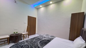 A bedroom with a bed, a chair, a small table, and two wardrobes. - It's Braj Raj Home Stay  (Mathura)