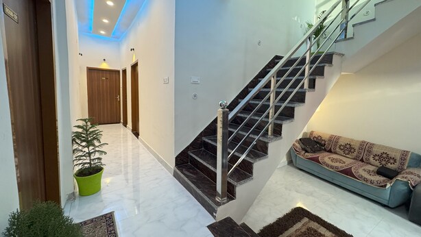 A modern interior with a staircase, a sofa, and a potted plant. - It's Braj Raj Home Stay  (Mathura)