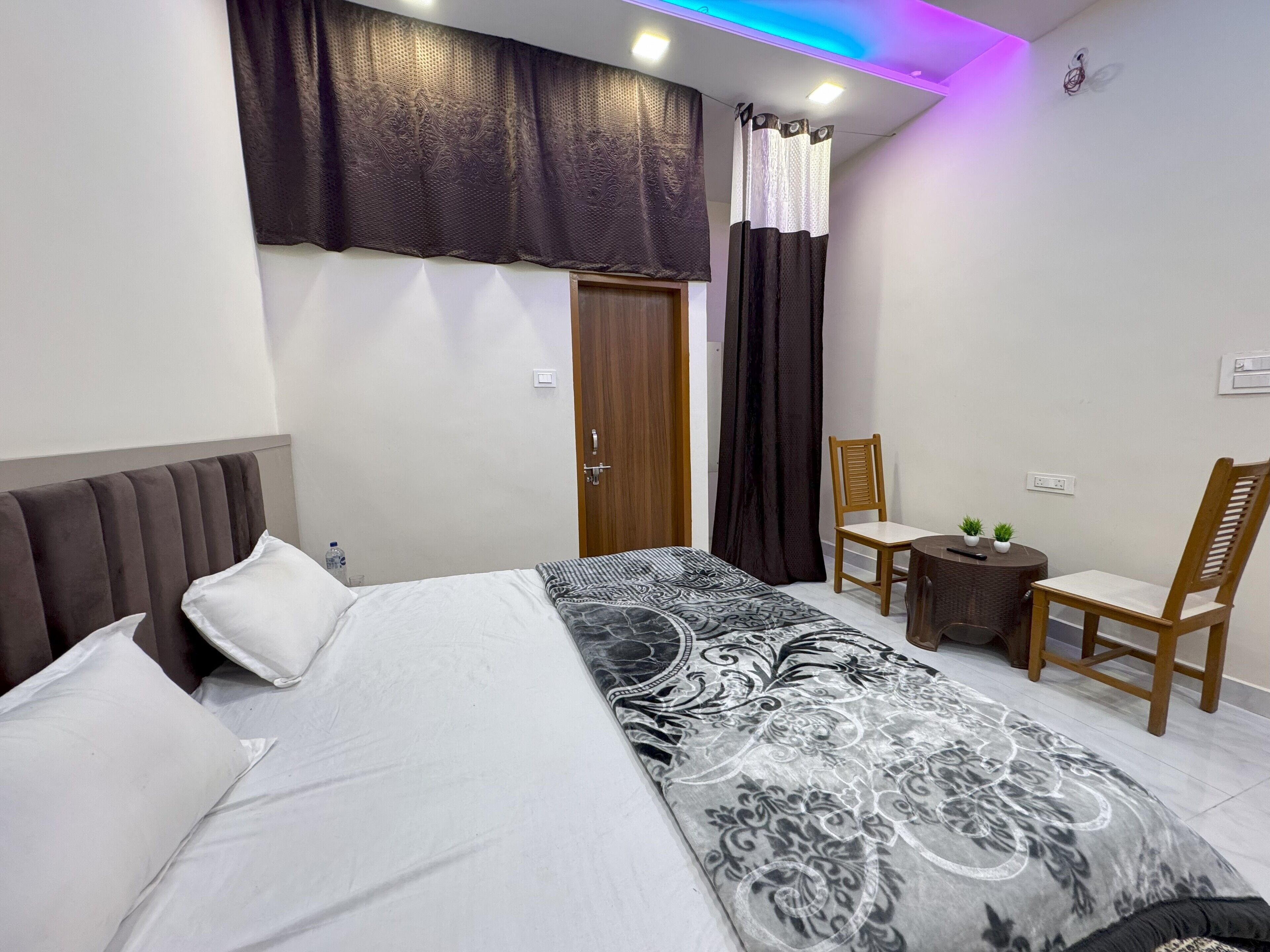 Ein Schlafzimmer mit einem Bett, einem Sessel, einem kleinen Tisch und einer Tür.