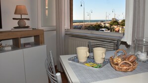 Un comedor con una mesa para dos, una lámpara y vista a la playa.
