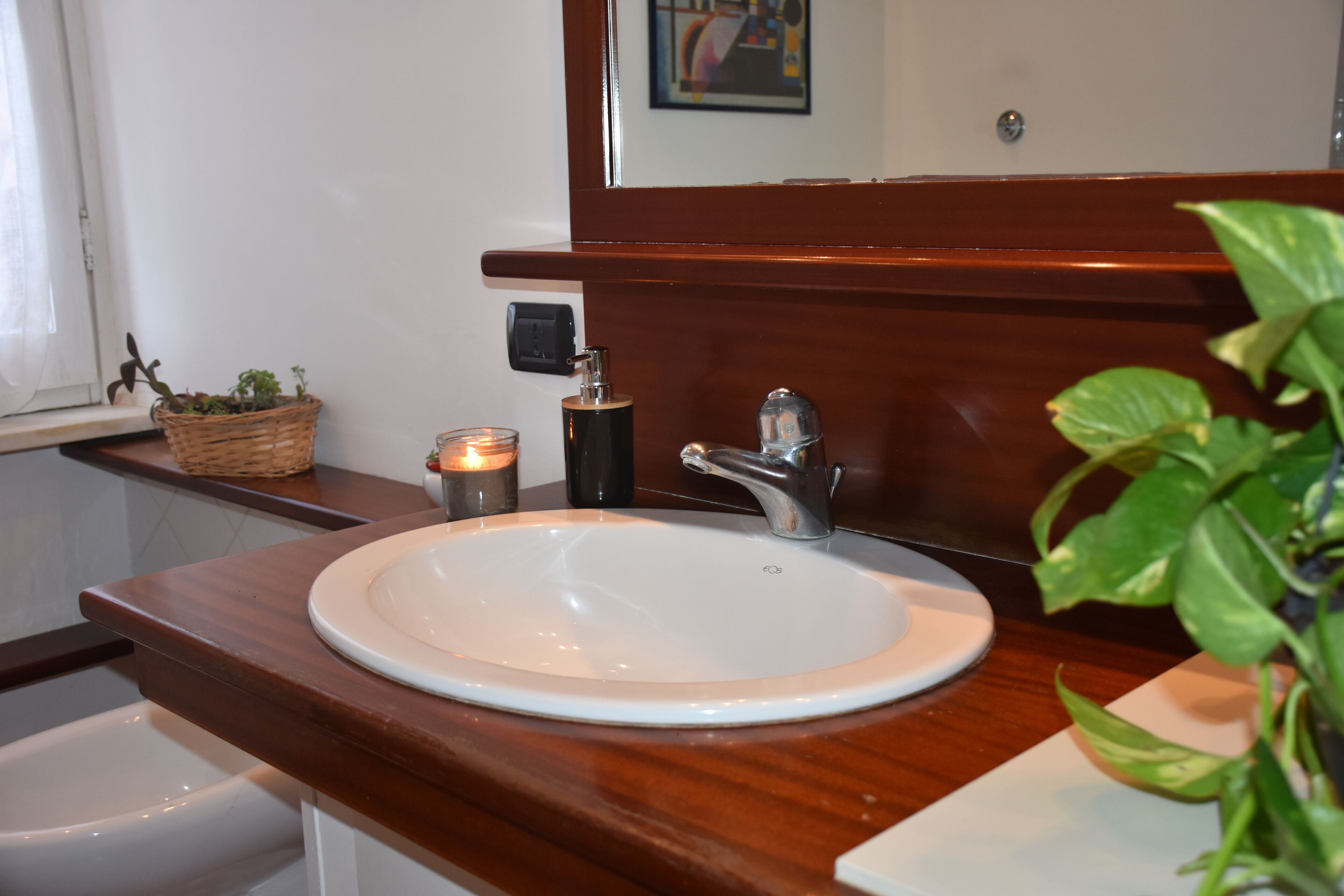 A bathroom with a white sink, wooden countertop, and a mirror above the sink.