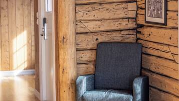 A wooden interior with a chair, wooden walls, a door, and a framed picture.