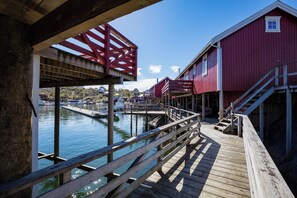 A wooden pier leading to a red building with a staircase.