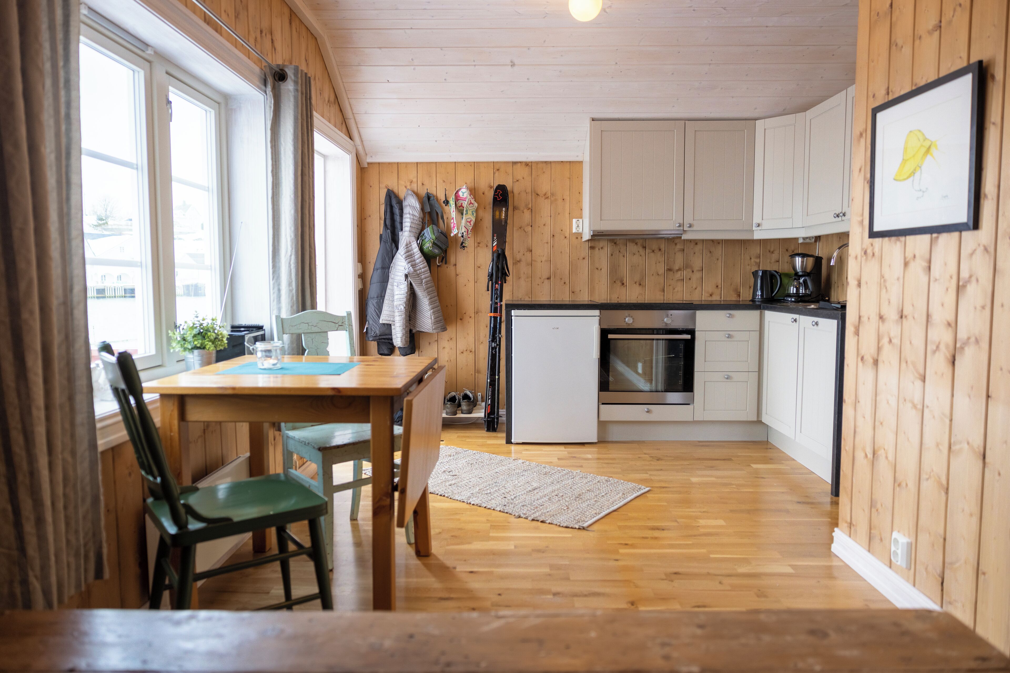 Un interior de madera con una zona de cocina, que incluye una mesa de comedor con sillas, un refrigerador y armarios.