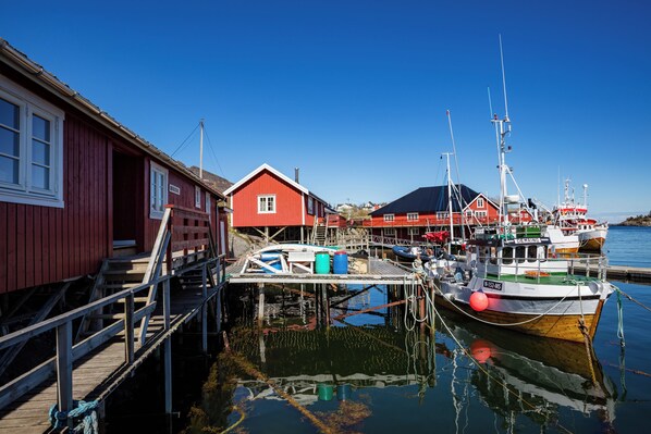 A harbor with a red building, a dock, and a boat named "DEHERRING".