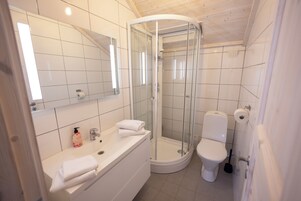 Un baño moderno con ducha de vidrio, inodoro y lavabo con espejo.