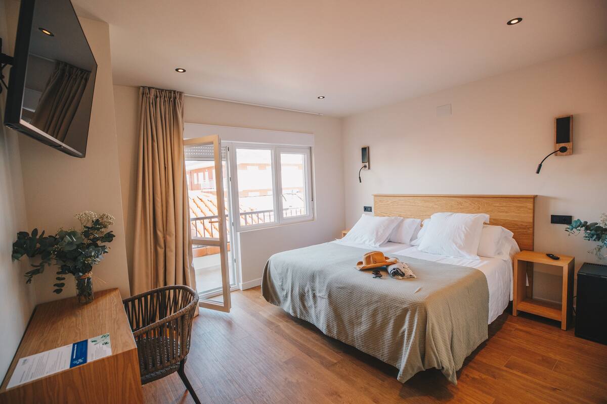 Une chambre d’hôtel équipée d’un lit, d’une table de chevet, d’une chaise et d’un téléviseur fixé au mur.