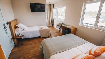 A hotel room with two beds, a desk, a chair, a TV, and a window with a view.