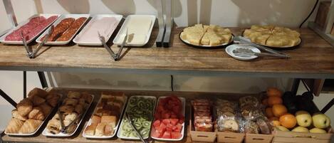 A buffet with various food items including meats, pastries, and fruits.